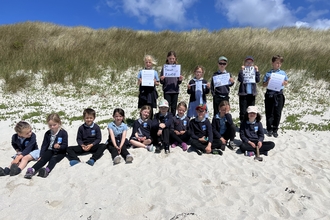 Children from St Martin's Base on the beach with their ringed plover signs